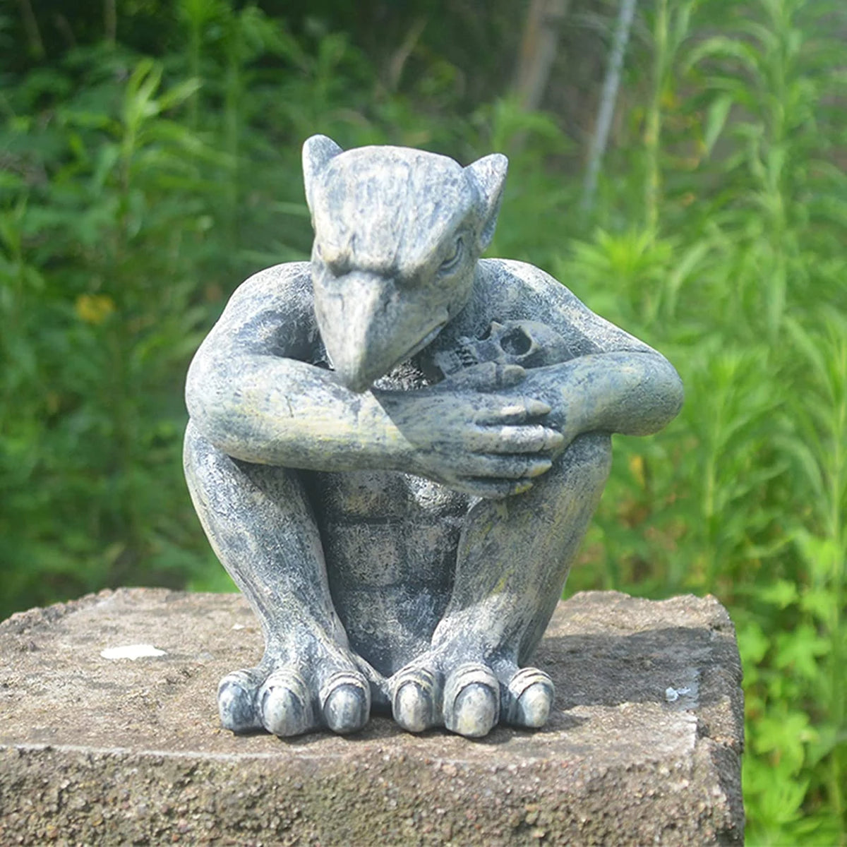 Vorreth the Gargoyle, crouching stone guardian statue clutching a skull, on a stone plinth outdoors