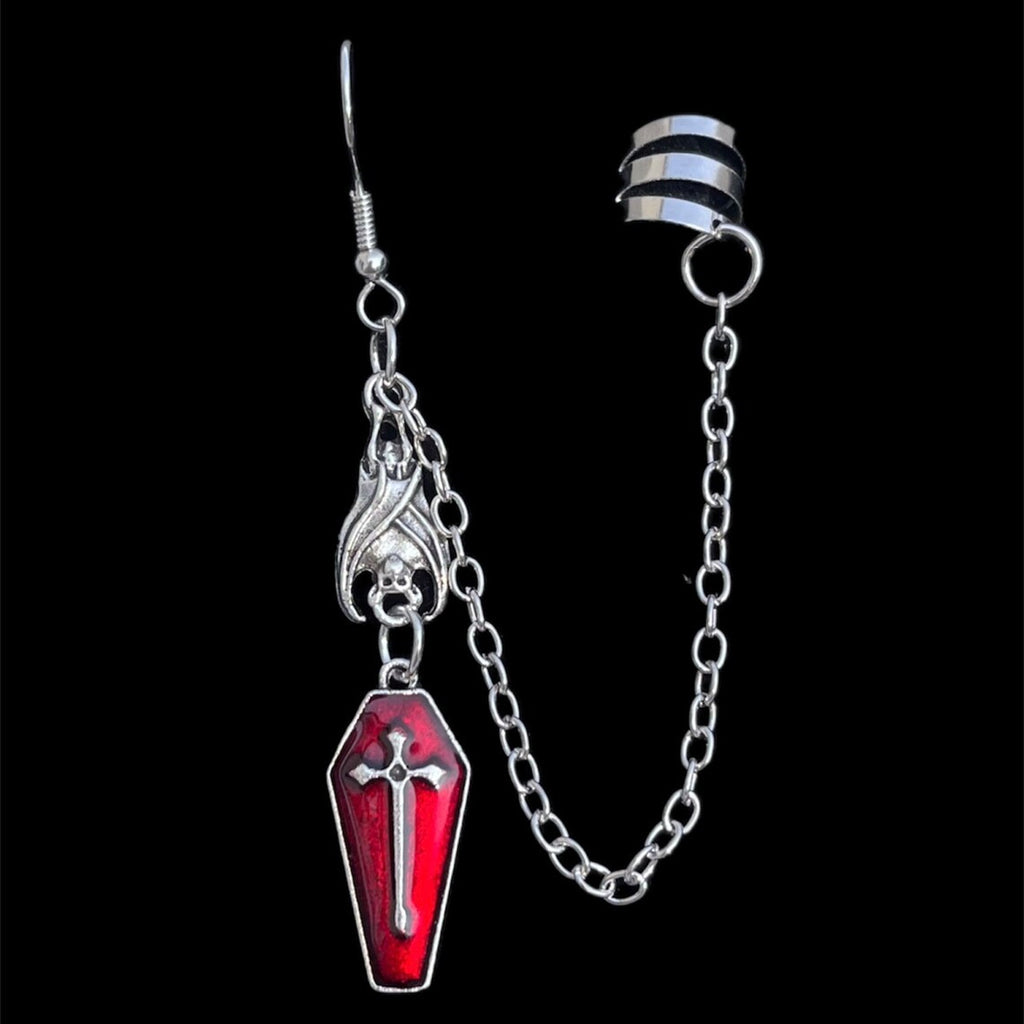 Silver ear cuff and chain with coffin charm, product view on black background