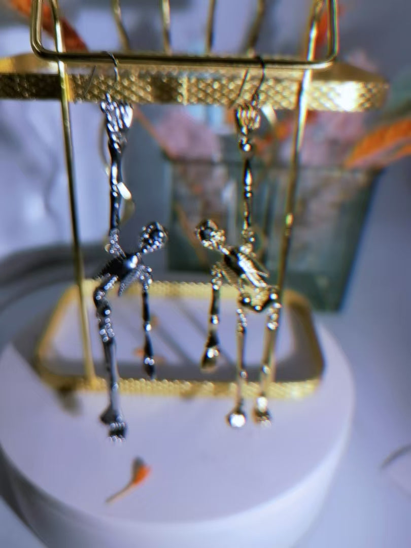 Pair of articulated skeleton dangle earrings on a display rack