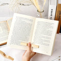 Wooden thumb page holder keeping a book open one-handed