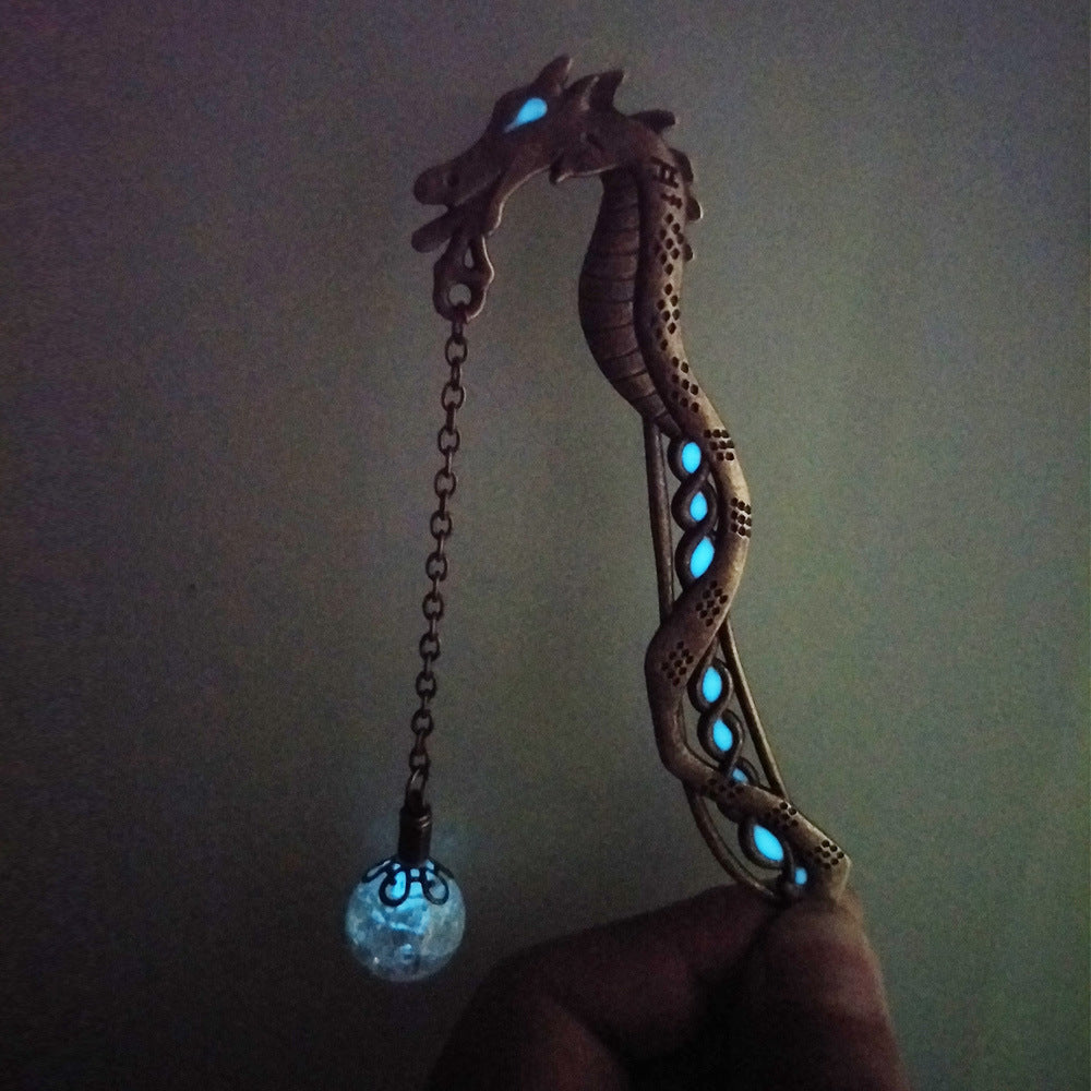 Metal dragon bookmark with luminous bead glowing blue in the dark