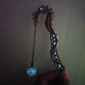 Metal dragon bookmark with luminous bead glowing blue in the dark
