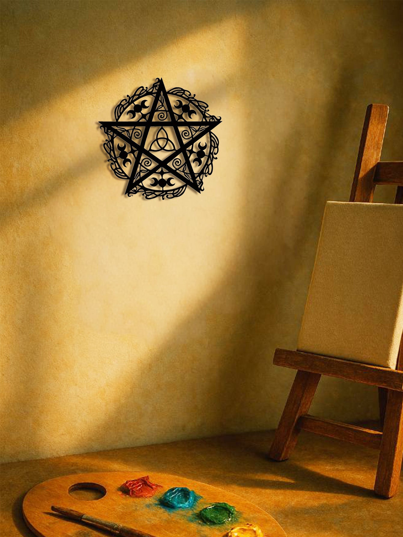 The Wyrdmark triple moon pentagram wall sculpture hung on a wall above an artist's easel