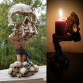 Skeletal hand candle holder rising from skull pile, lit candle