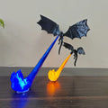 Two black 3D-printed dragons suspended on glowing blue and orange LED flame columns on a dark wood shelf
