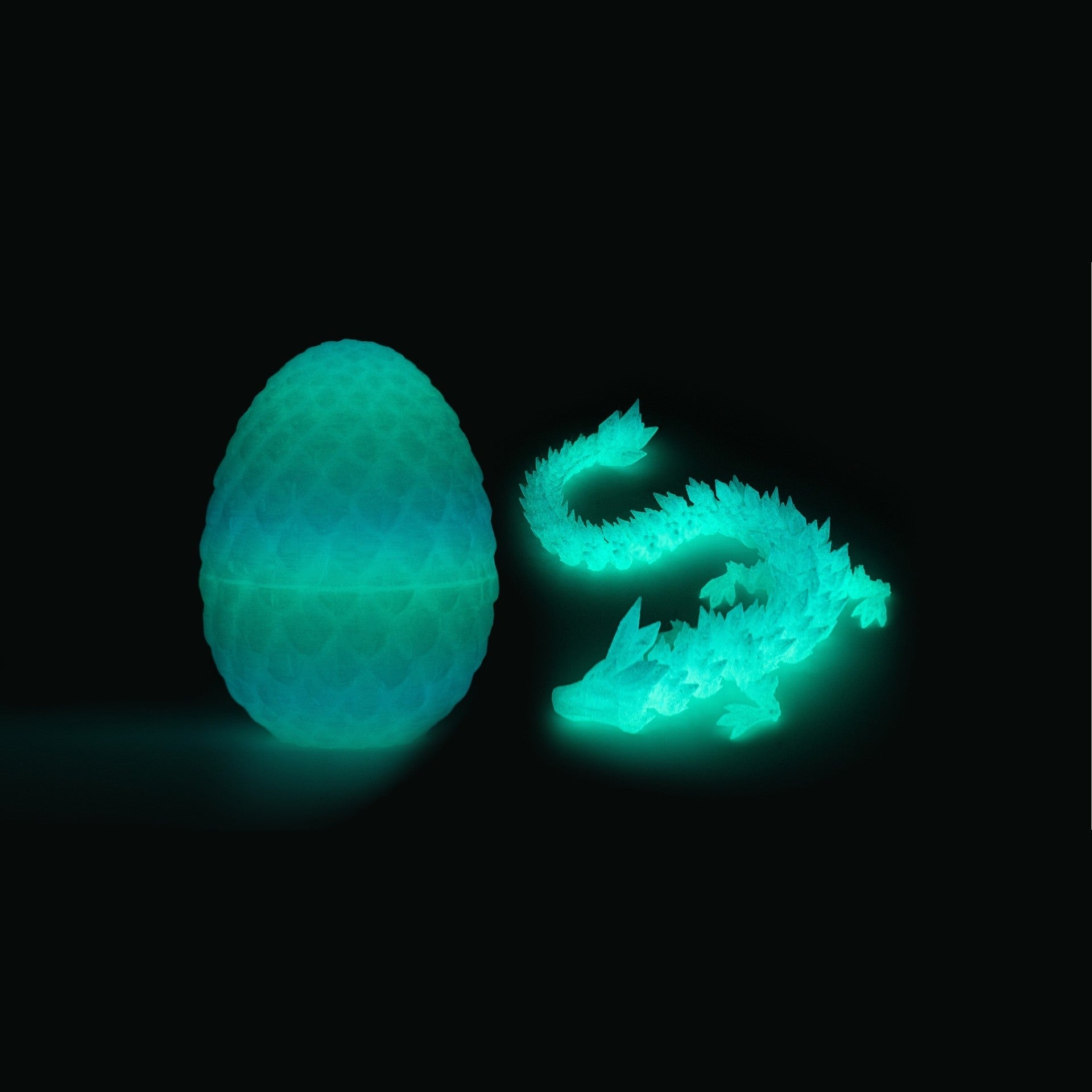 Luminous dragon egg and articulated dragon glowing teal in the dark