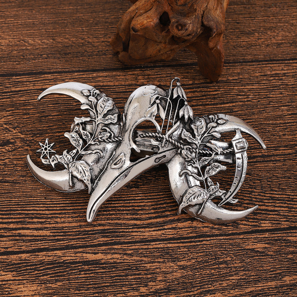 Antique silver raven skull hair clip with crescent moons, ivy, and star charm, angled detail view