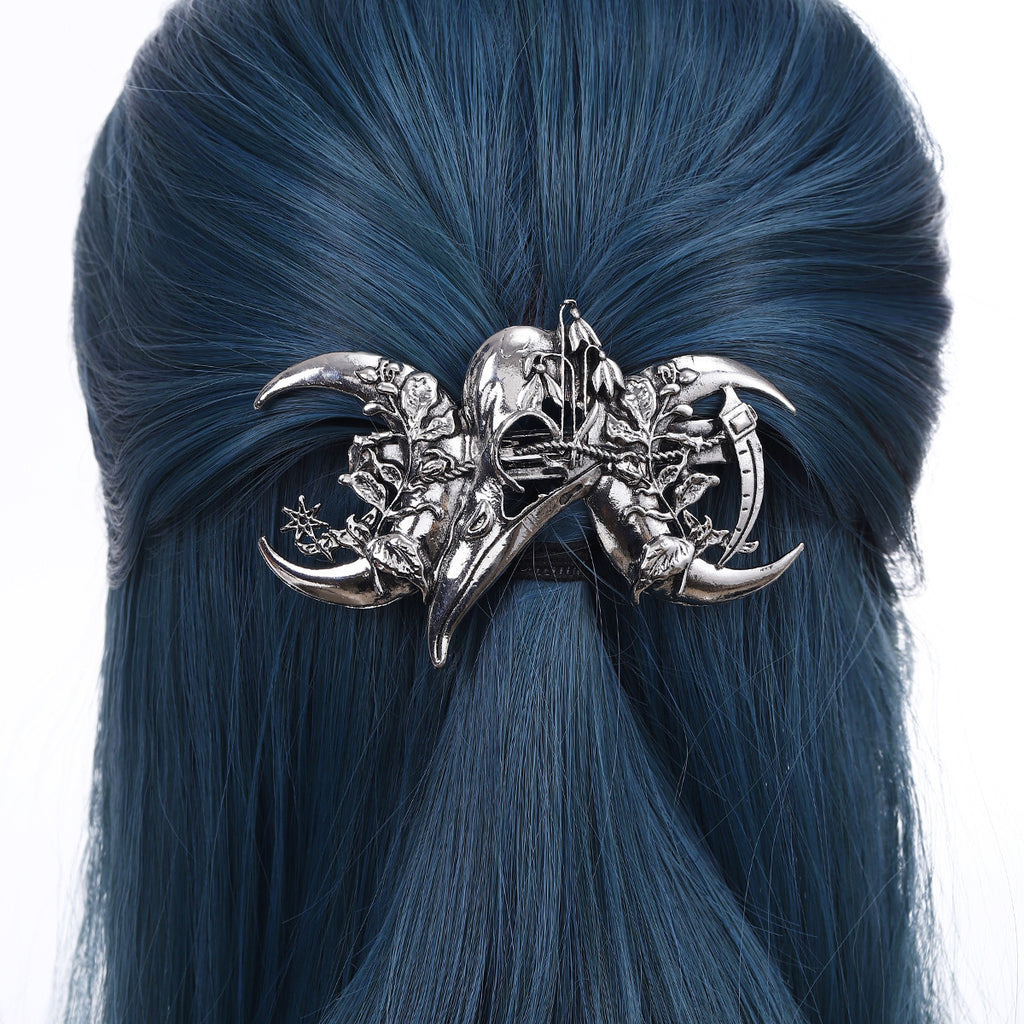 Antique silver raven skull hair clip with crescent moons, worn in dark hair