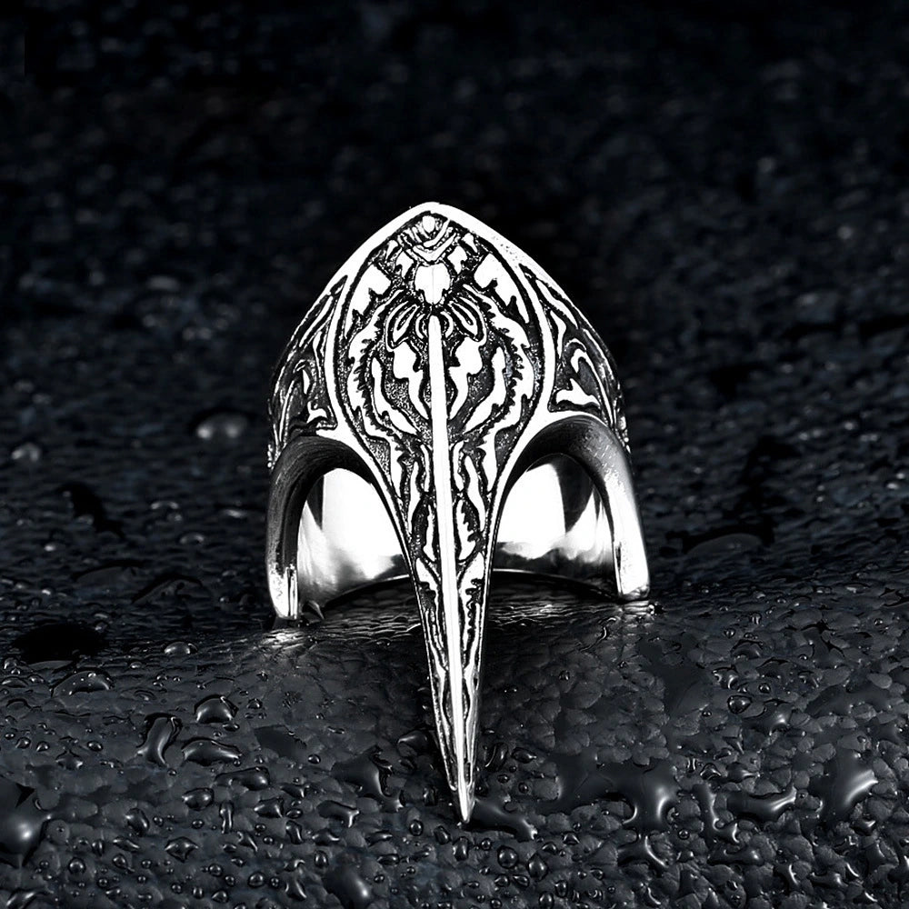 Hexbound Raven Ring, carved titanium band with raven-skull crest engraving, on dark wet stone