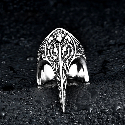 Hexbound Raven Ring, carved titanium band with raven-skull crest engraving, on dark wet stone