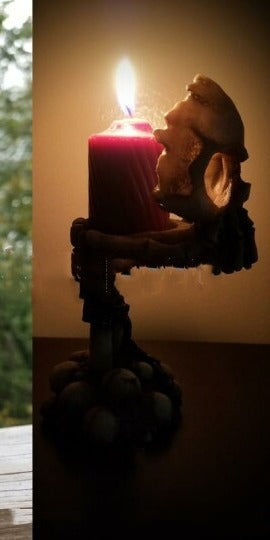 Vigil's Grasp candle holder at night with a lit red candle casting warm gothic light